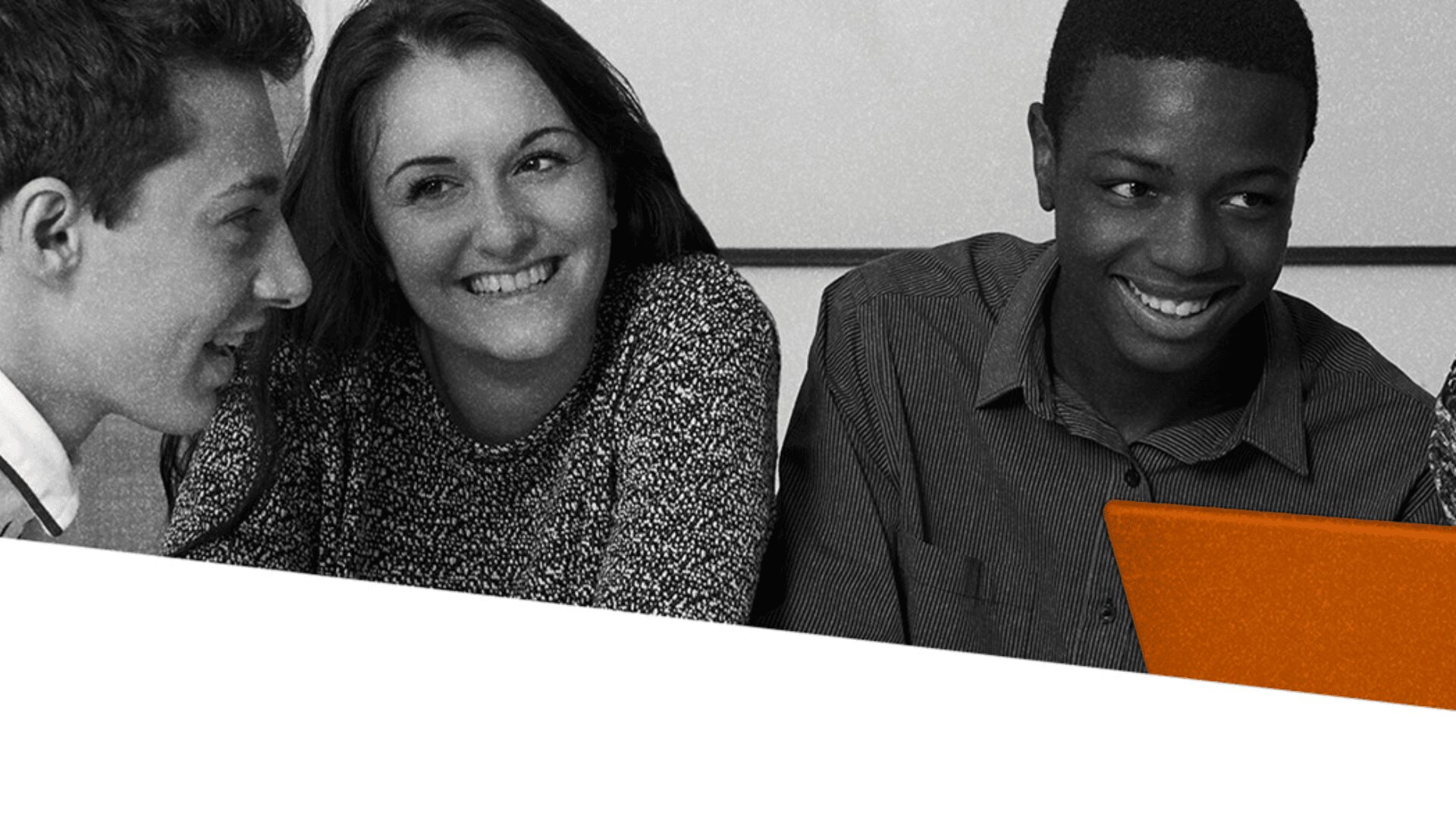 Trois jeunes gens, deux hommes et une femme, sourient et discutent ensemble. Un ordinateur portable orange est partiellement visible devant eux. L'arrière-plan semble être une salle de classe ou un lieu d'étude.