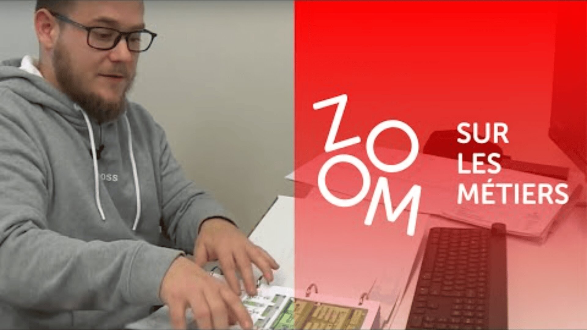Un homme vêtu d'un sweat à capuche gris est assis à un bureau avec des documents et un clavier. Le côté droit de l'image est recouvert d'une couche rouge avec les mots ZOOM SUR LES MÉTIERS en blanc.