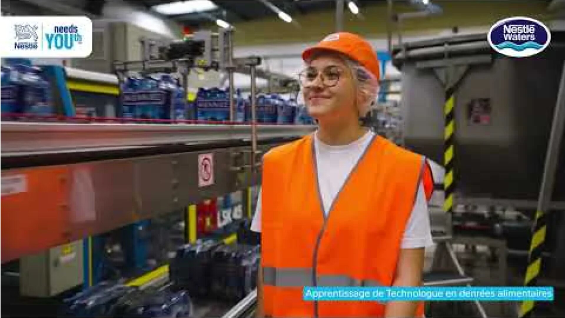 Une personne portant un gilet de sécurité et un casque orange sourit à côté d'un tapis roulant contenant des bouteilles d'eau dans une usine. L'image comporte des logos de Nestlé et un texte en français au bas de l'image.