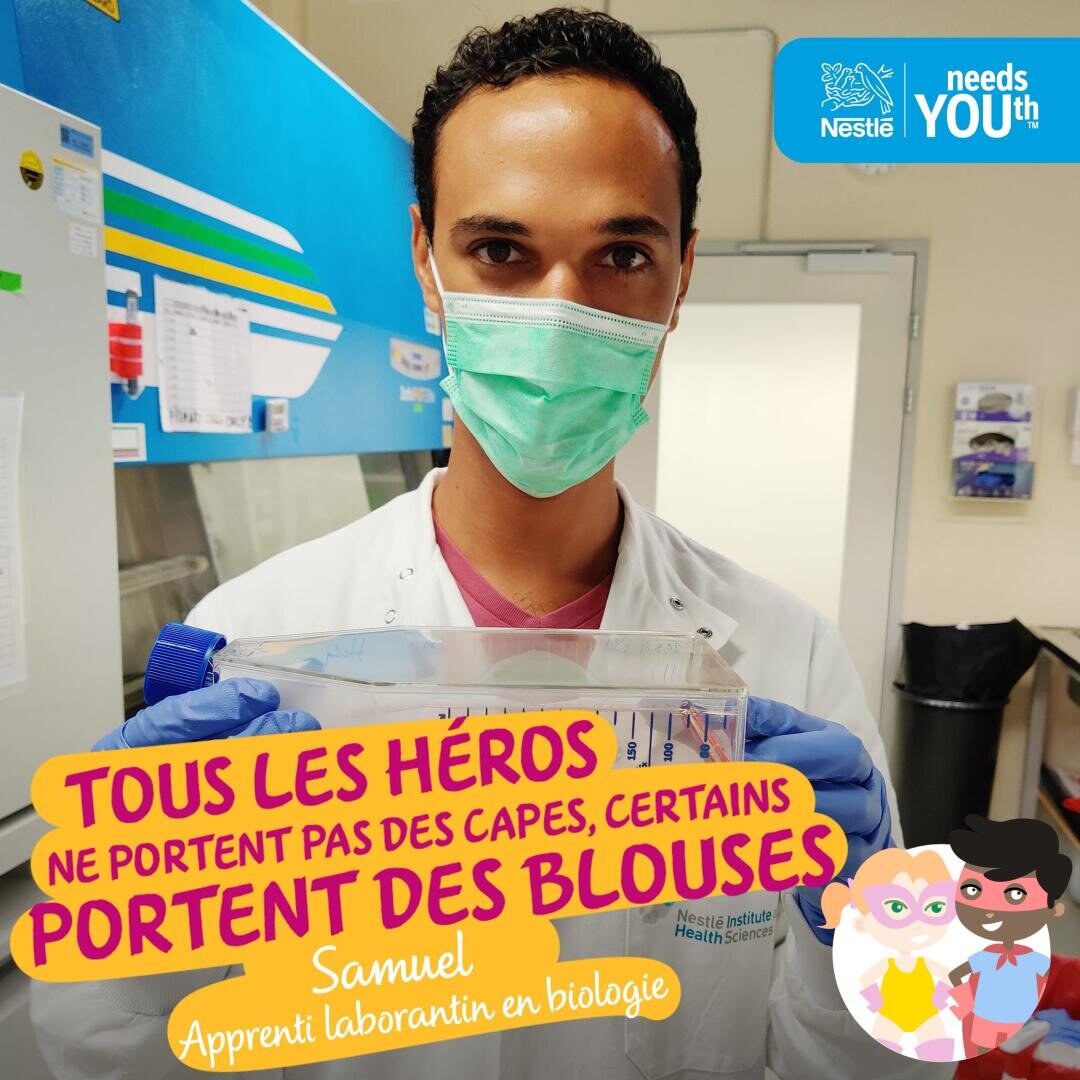 Un jeune technicien de laboratoire en blouse blanche, gants et masque tient un plateau de laboratoire. Le texte illustré en français dit : "Tous les héros ne portent pas de capes, certains portent des blouses de laboratoire". Le logo "Nestlé Needs Youth" apparaît en haut à droite.